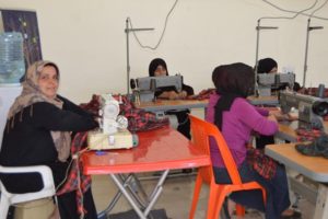 Ameera sewing school uniforms at work.