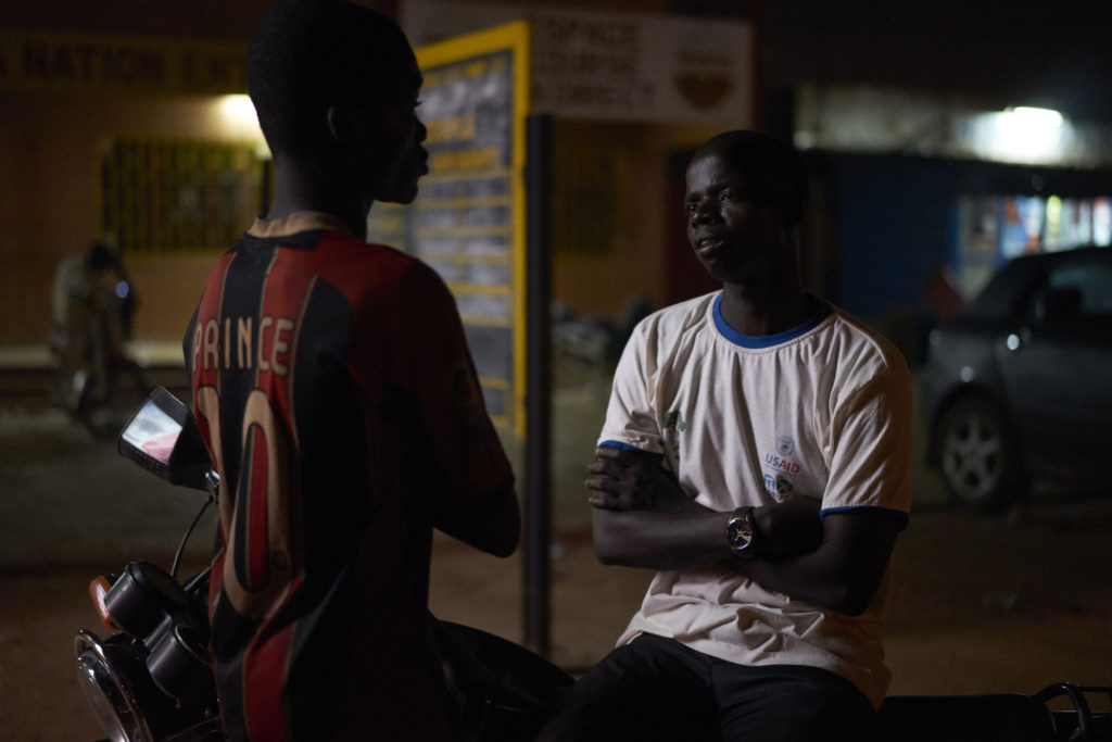 Tasséré Ouedraogo talks with a boy living in the streets in Ouagadougou, Burkina Faso on October 5th, 2016. Tasséré Ouedraogo is Executive Secretary of "Association de Jeunes et enfants vivant dans le rue face à leur sort". PDEV supported the association with materials including motorbikes, desk, chairs and other office equipment and workshops in peace-building. Some of the boys ended up on the street having fled Koranic school, some were victims of domestic violence and others orphans. The boys at this particular site are between 13 and 18 years old and sleep here because the night guard permits their presence and offers some form of protection from street violence. The kids talk about their problems at the moment they are facing and the social workers take these into consideration and actions that can be taken to resolve them. During the day they search everywhere for scrap metal that they can sell for about 5-6000 CFA. Tasséré says The associations objective is to assist children who are living in the streets. We were street kids ourselves so when we got off the streets and started working we wanted to do something to help others like us. We identified 45 sites in the city where you will find street kids and then identified one of the kids from each site as a team leader. We realised that it is important to find a leader amongst the kids who could raise important issues related to hygiene, health and substance abuse. In the past what happened was the kids were stigmatised when there were thefts in the community. We realised that our activities alone would not be sufficient to help these children out of their situation and we needed to engage the community, without this assistance the kids can't get off the streets and they will keep being stigmatised. We created football matches that were played in each neighbourhood, it allowed the children to make friends in these neighbourhoods with other kids through playing together and also the community le