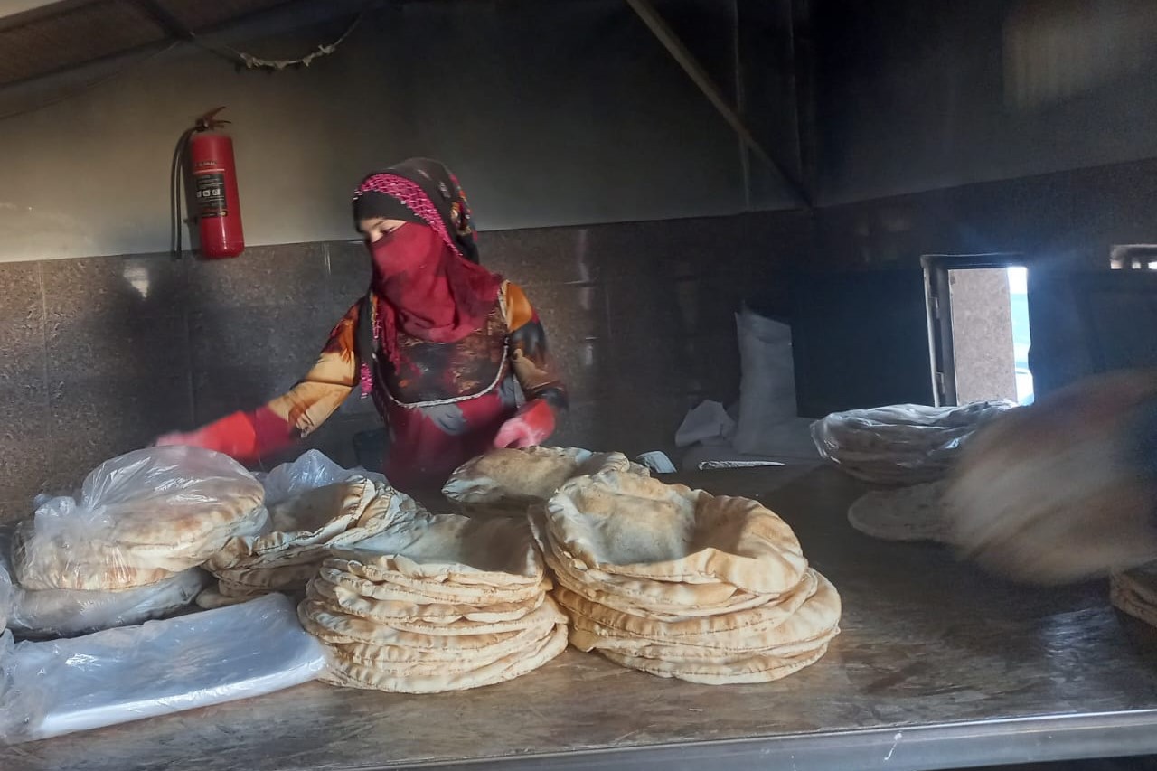 woman holding bread inside of a gender inclusive bakery