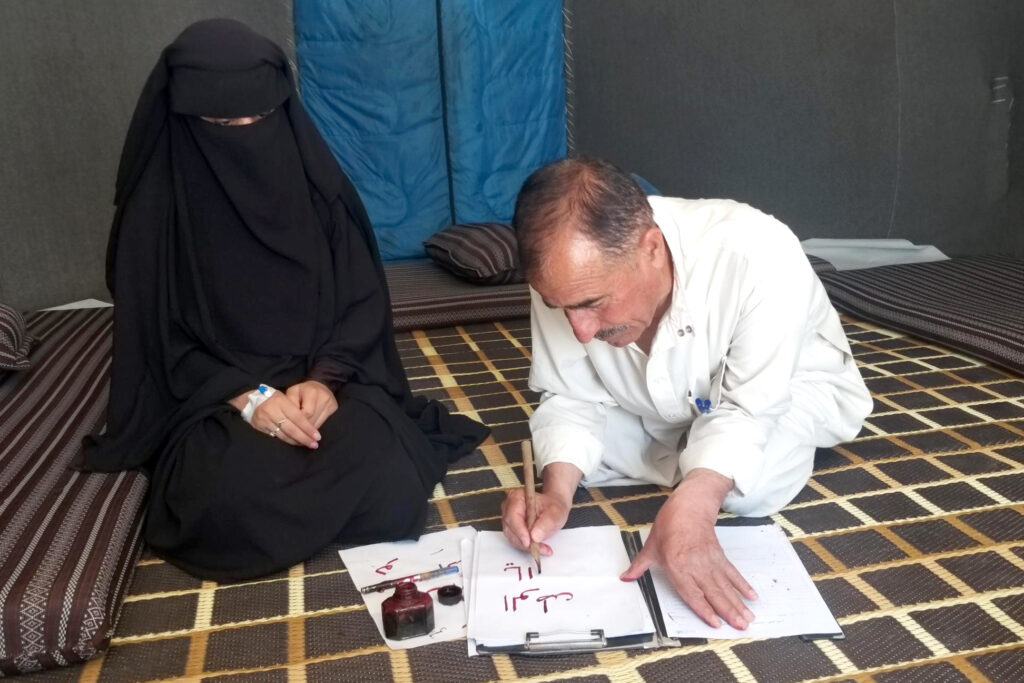 man writing in calligraphy next to woman