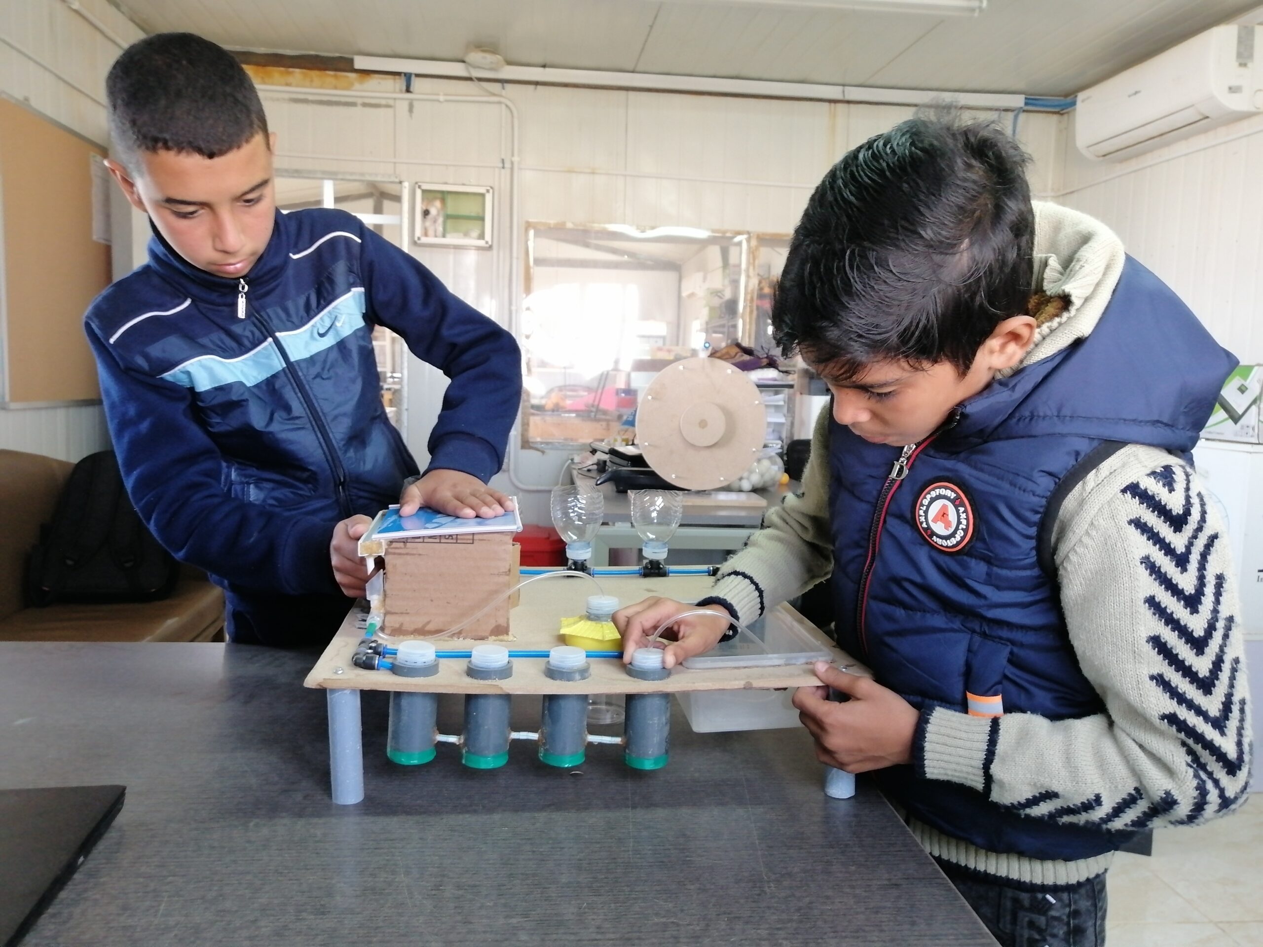 two young refugee boys working on a climate change solution prototype