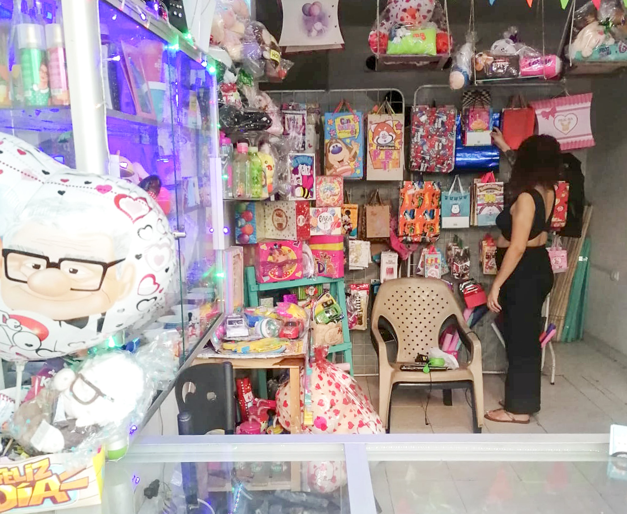 a woman who is facing away from the camera looks at shelves full of gifts and stationery
