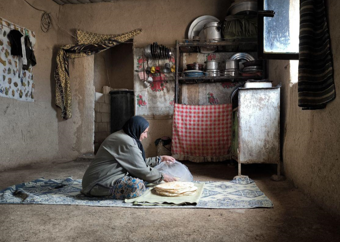 a woman sits on the floor of her kitchen with a package of bread in front of her