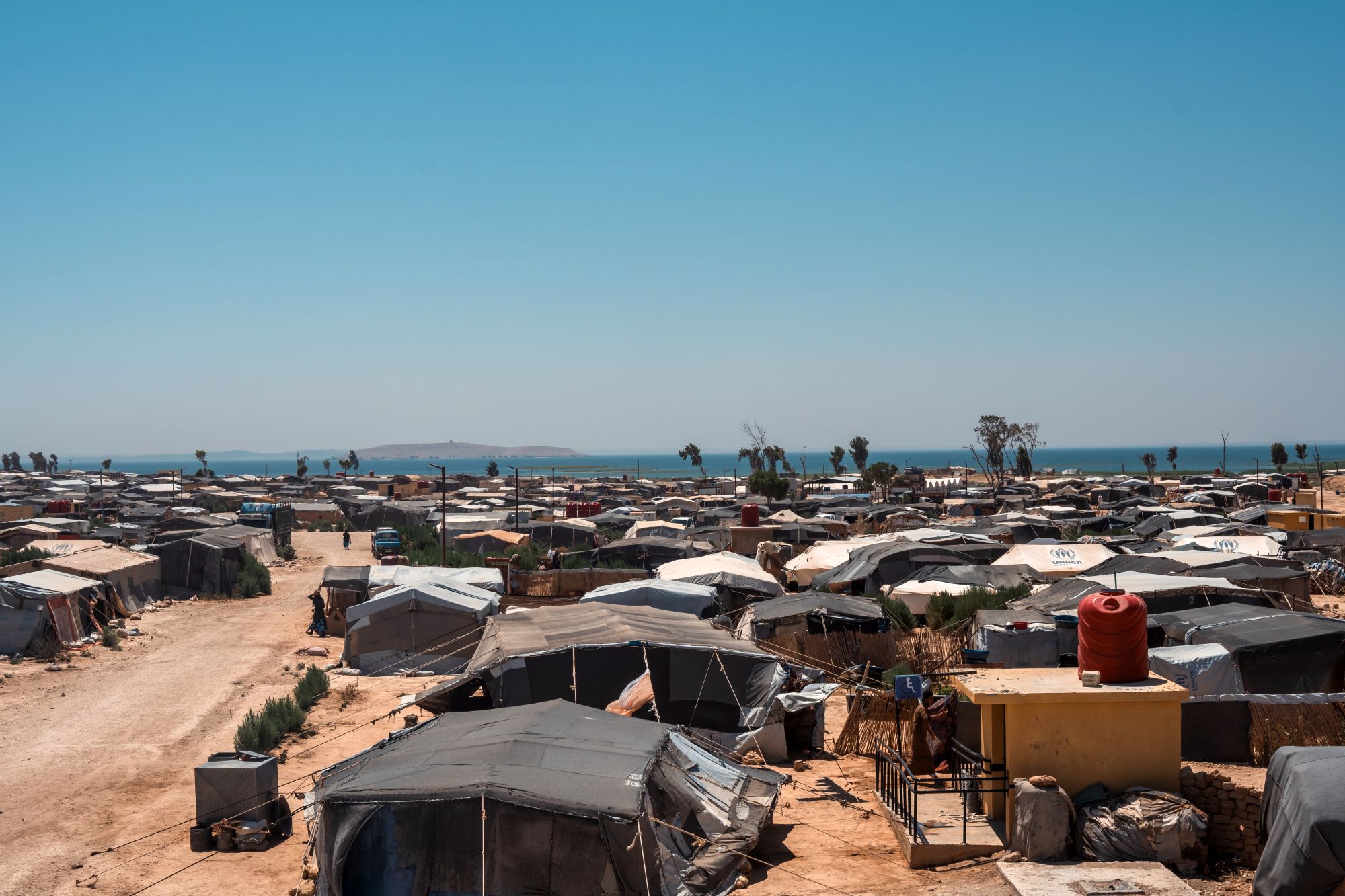 A view of a displacement camp from above with a lake at the horizon