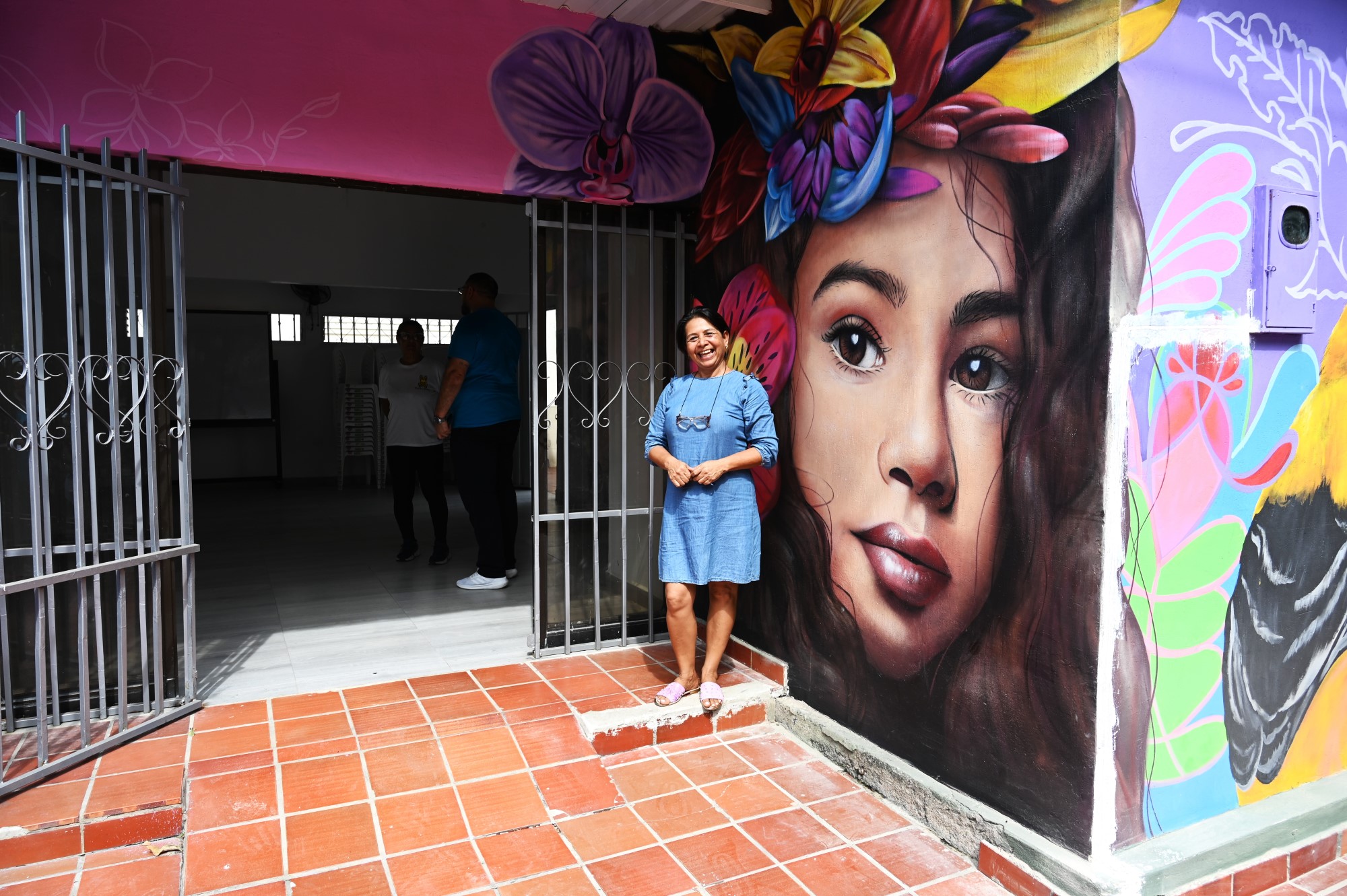 woman stands in front of colorfully painted building